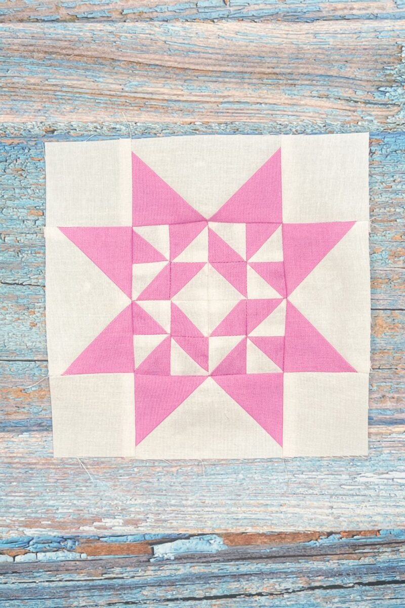 Twilight Stars QAL week 11 block 24. This block is made of half square triangles offset by flying geese and corner blocks. It is white and light purple