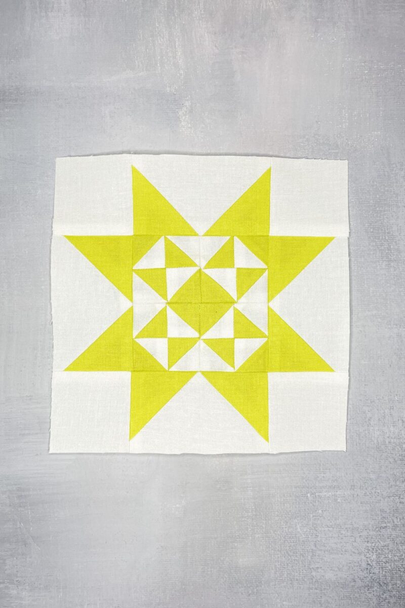 Twilight Stars block 77 in yellow and white. Features half square triangles for the center and flying geese frame.
