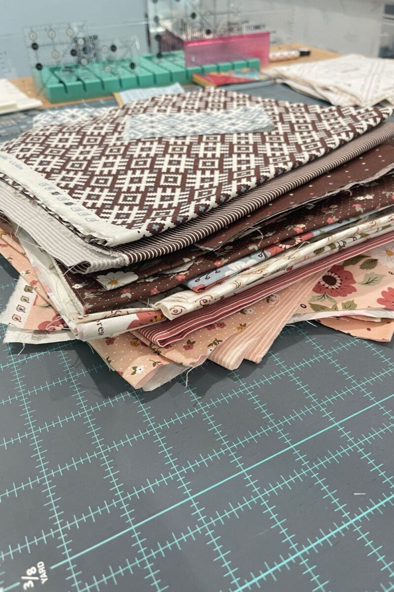 Scrap fabrics from the Folktale fabric collection. Fabrics are brown, blue, cream, and pink.