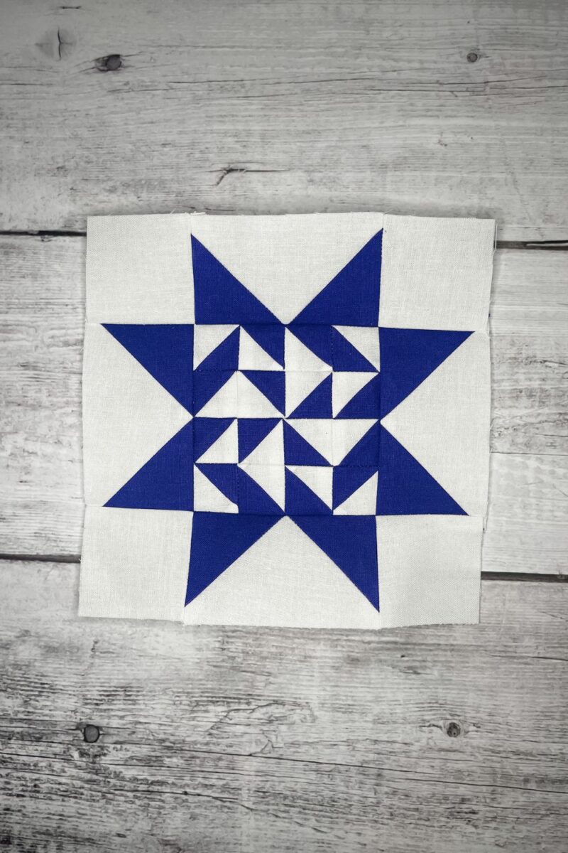 Quilt block 89 for the Twilight Stars Quilt Along with Lisa Bongean. The block is dark blue with 16 half square triangles making up the centers and flying geese sides completing the star blocks