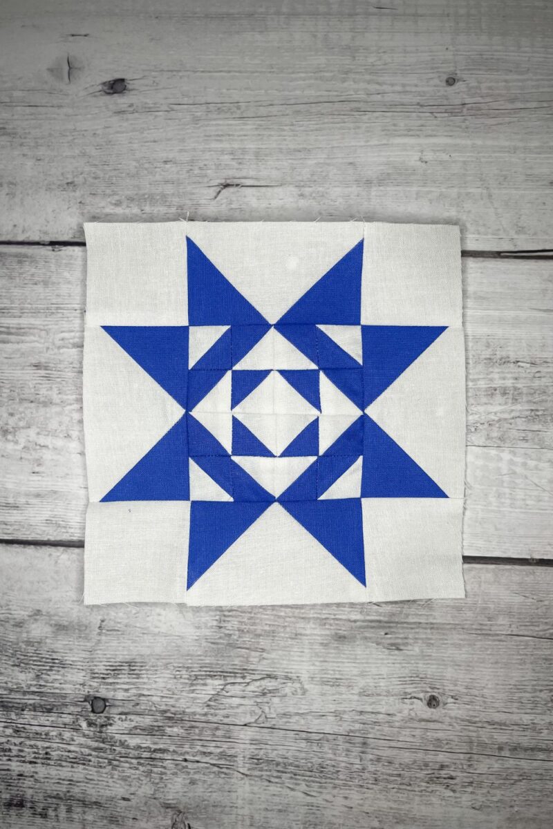 Quilt block 6 for the Twilight Stars Quilt Along with Lisa Bongean. The block is dark blue with 16 half square triangles making up the centers and flying geese sides completing the star blocks