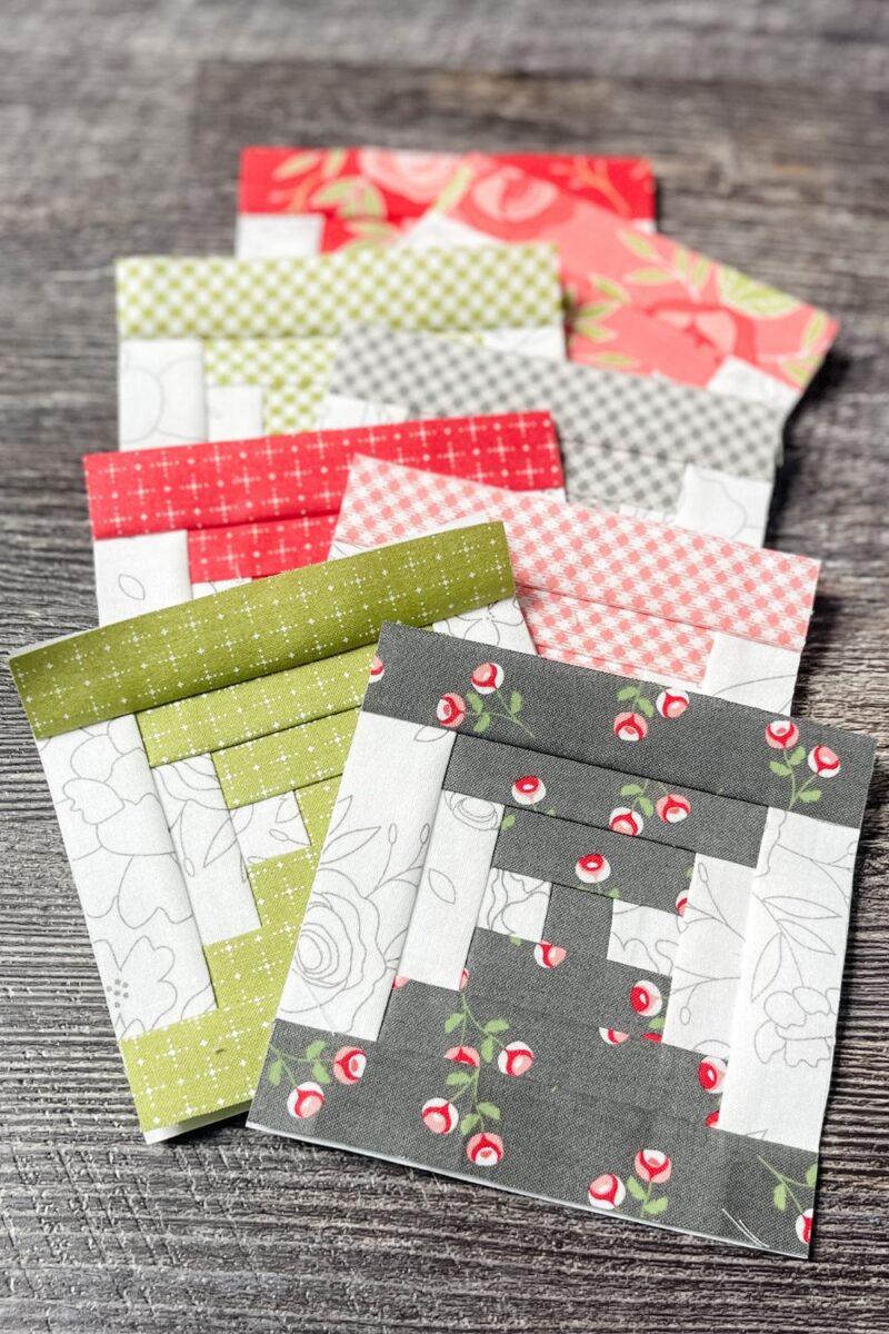 8 finished courthouse steps quilt blocks using Beautiful Day fabrics in grey, green, pink, and dark pink.