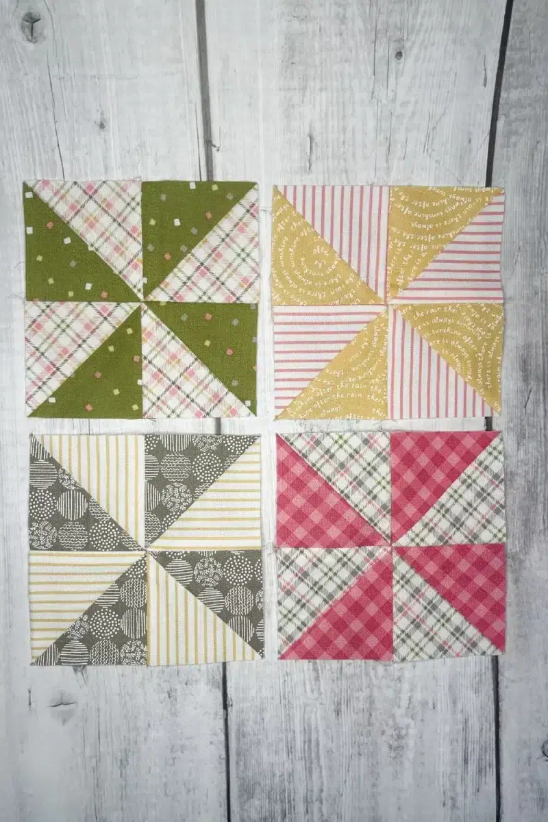 Whirligig quilt blocks made with 4 half square triangles. Blocks are made in green, yellow, grey, and pink.