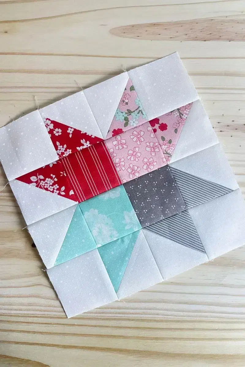 The Beehive block is made of red, pink, aqua, and grey four patch center and coordinating star points made with half square triangle blocks