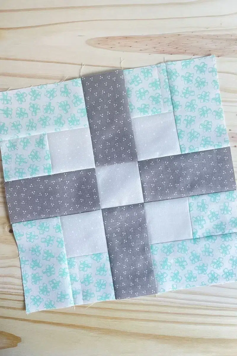 The Bliss block is made with modified four patch corners in teal and white with a grey criss cross of fabric in the center.