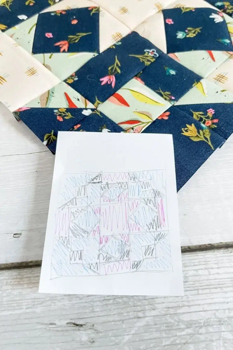 Community Star quilt block in Songbook fabric collection. Block is primarily navy floral with square in a square and nine patch components. Also shows sketch of how I assigned colors to the block