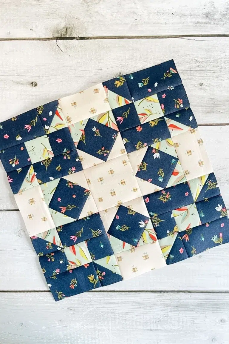 Community Star quilt block in Songbook fabric collection. Block is primarily navy floral with square in a square and nine patch components.