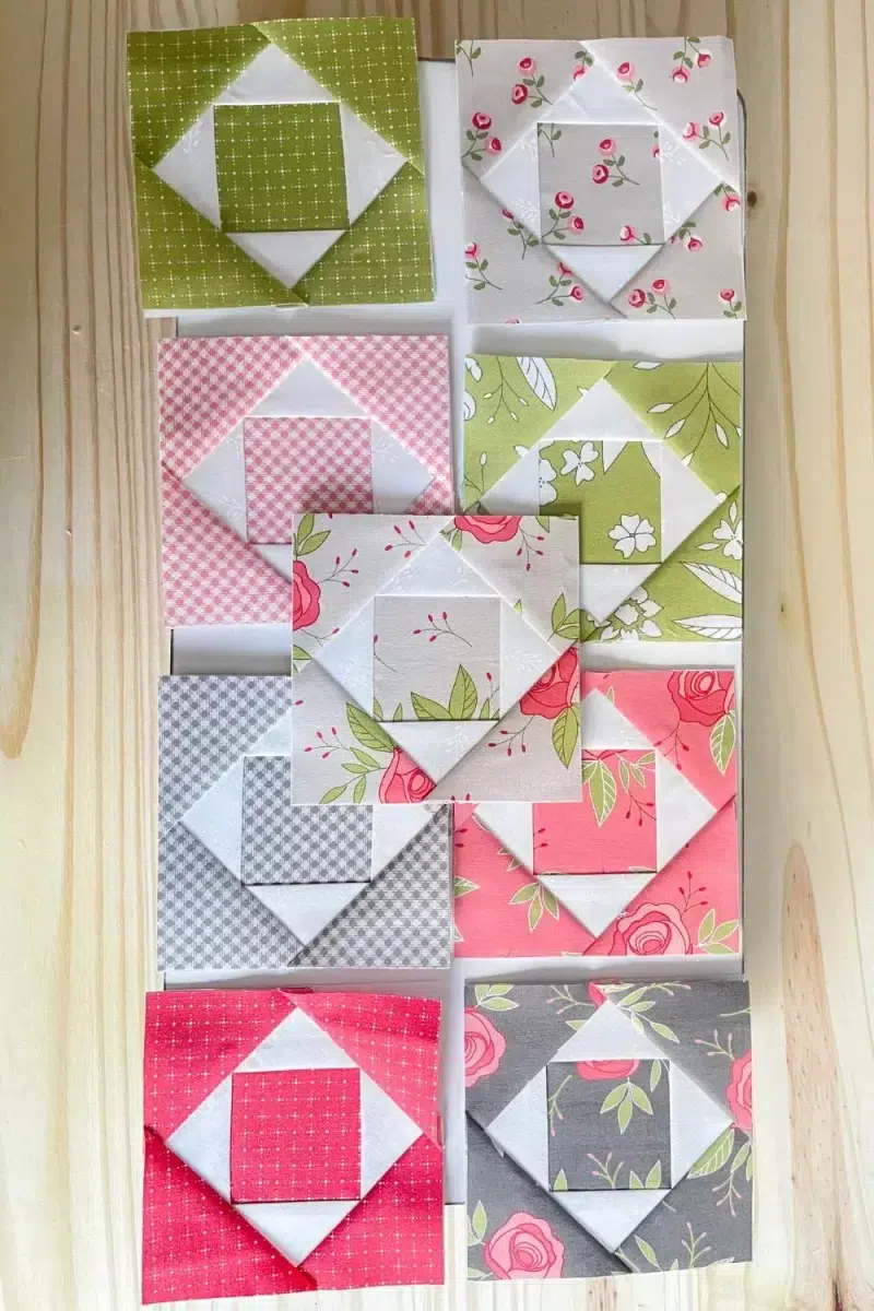 Economy quilt blocks in grey, green, pink, and red offset with white.