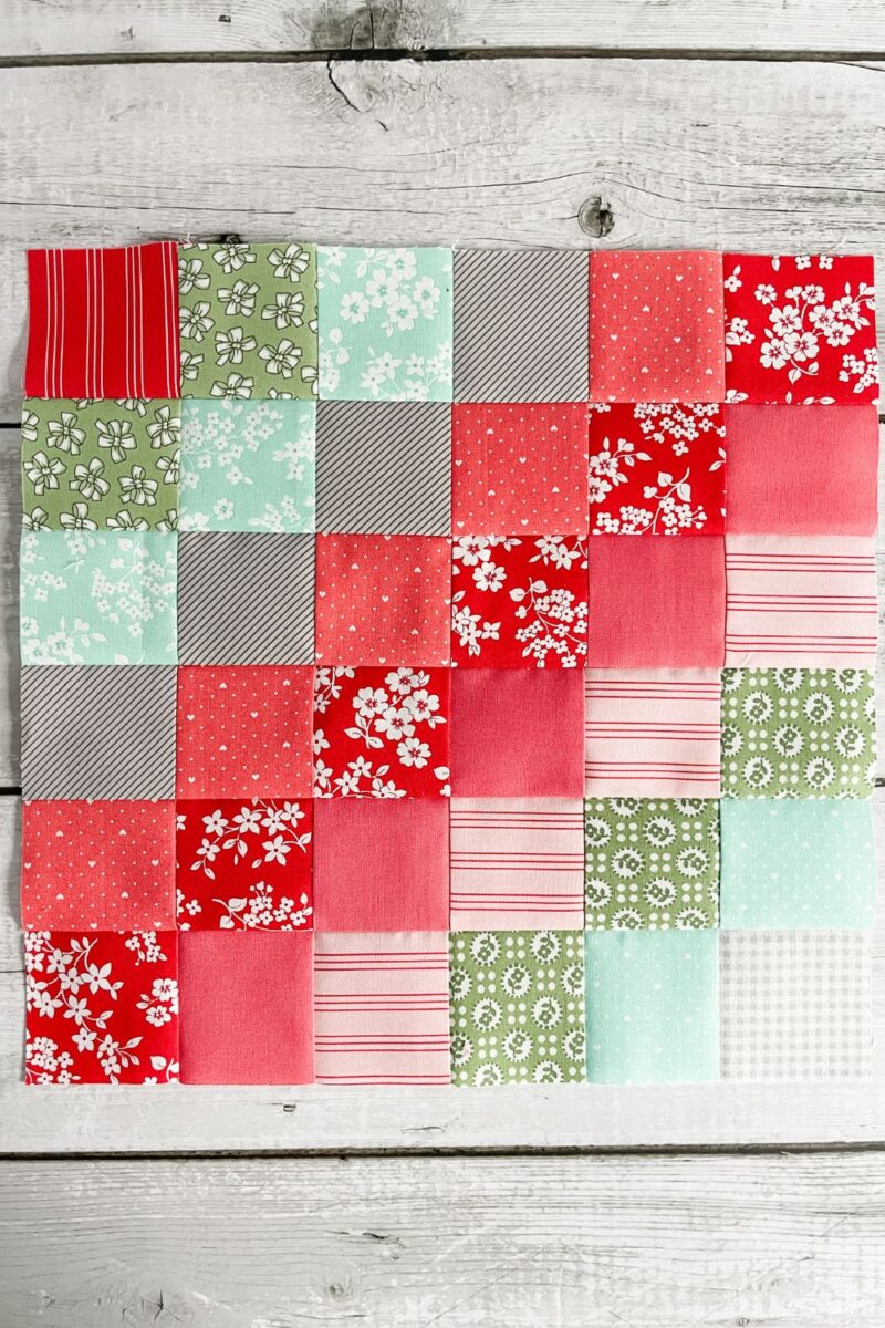 a 36 patch quilt block in pinks, grey, reds, green, and teal.