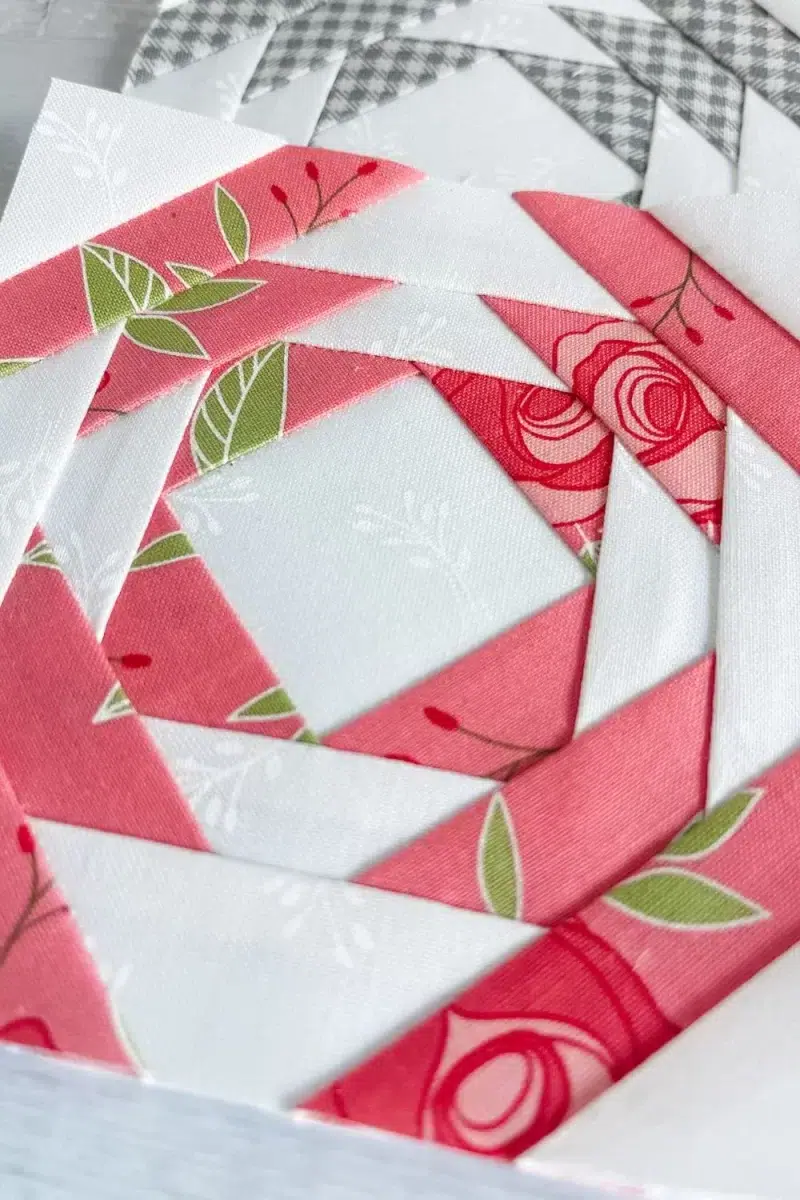 Close up view of a pineapple quilt block in dark pink and white.