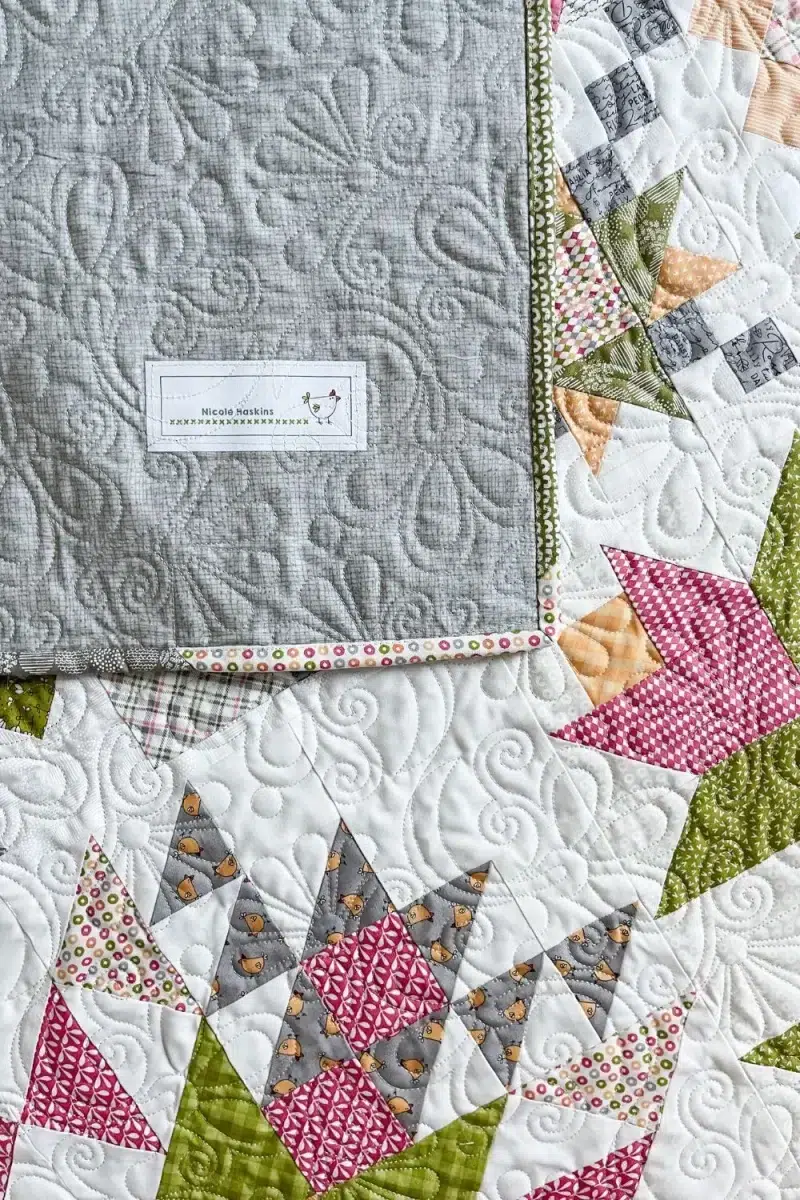 Quilt is folded on itself showing the backing and quilt label.
