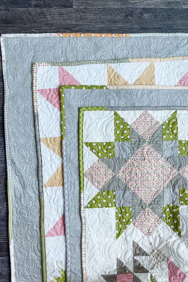 Four folded corners of the completed barn star sampler quilt showing the scrappy binding.