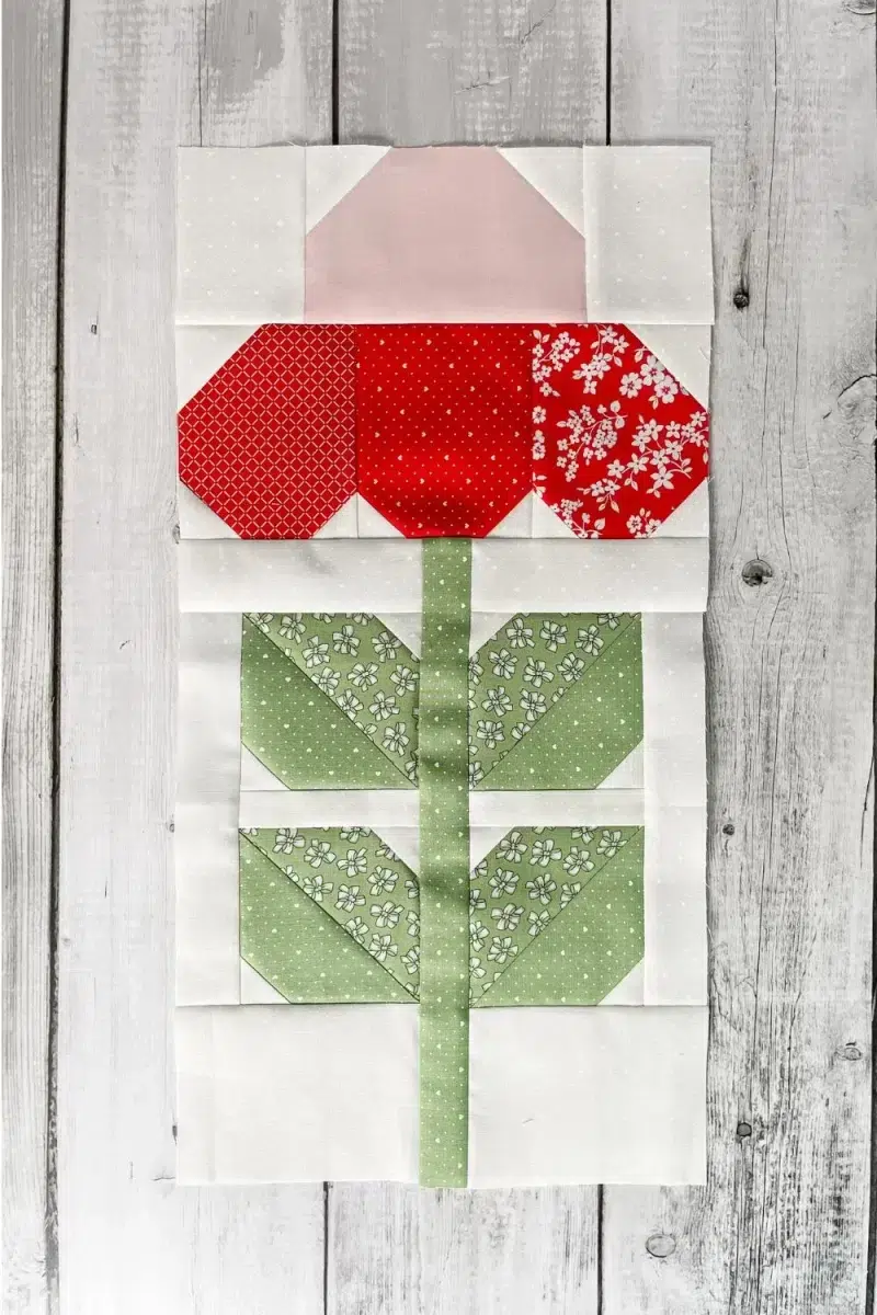 Flower quilt block with pink center and red petals.