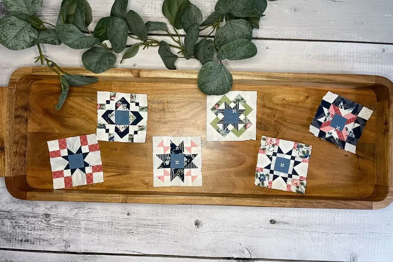 6 mini quilt blocks in a wooden tray