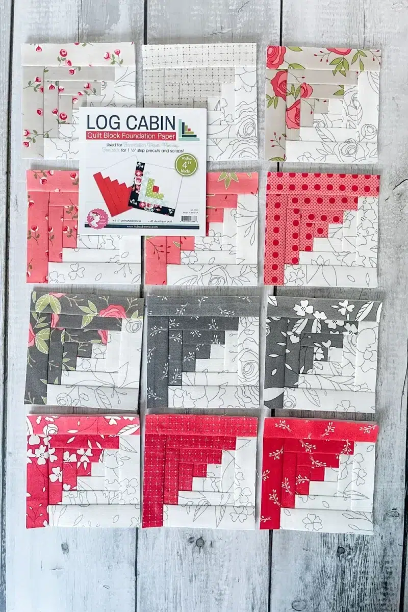 Paper pieced log cabin blocks with half of each block in a grey and white pencil sketch print and the other halves in pink, tan, dark gray, and red floral printed fabrics. 12 blocks all together.