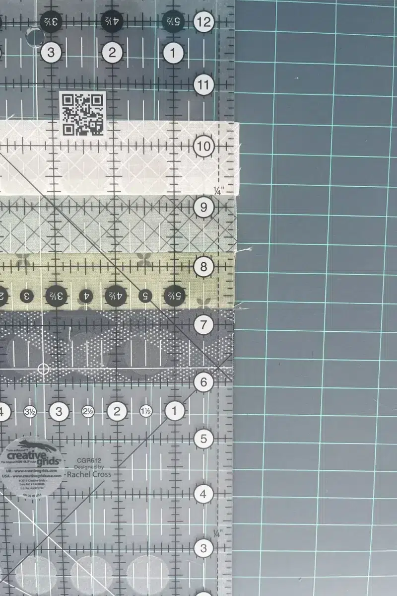 Using a quilting ruler to trim the uneven edge of a strip set