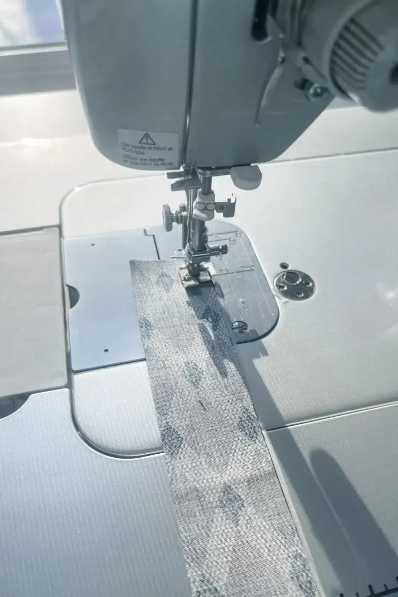 Sewing machine piecing together two long strips of fabric.