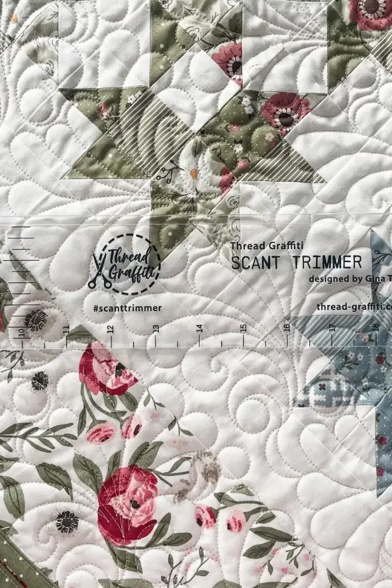 The Scant Trimmer by Gina Tell of Thread Graffiti. It is a 20 inch long ruler with a raised edge to precisely trim a finished quilt to prepare it for binding.