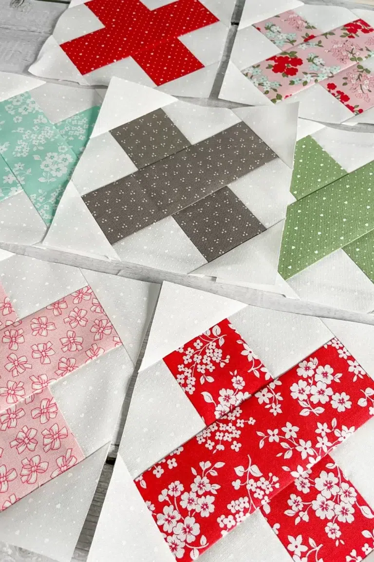 Cross Stitch quilt blocks in red, pink, aqua, green, and grey.