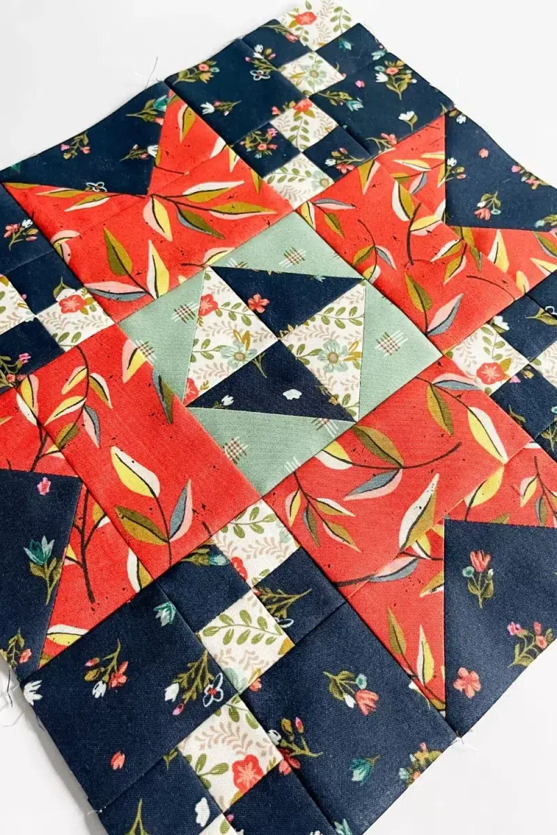 Sparkle quilt block in red, sage, navy, and white florals quilting fabrics.