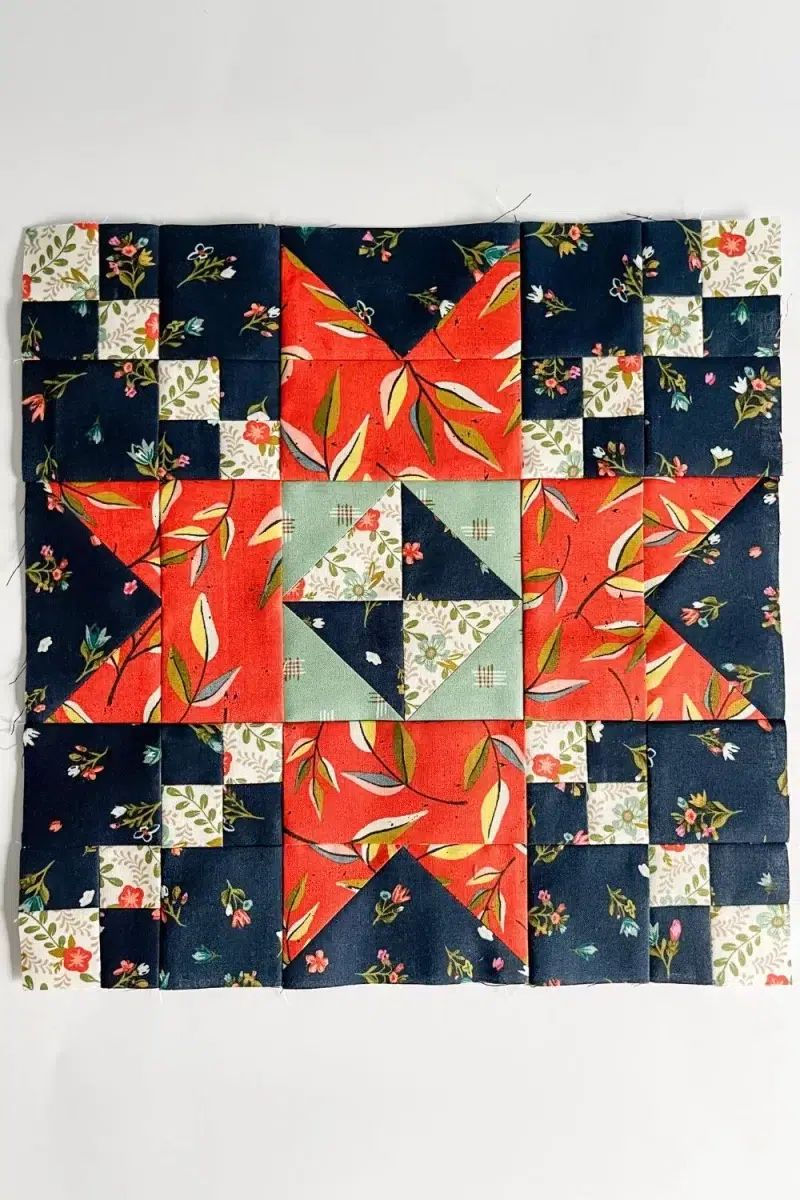 Sparkle quilt block in red, sage, navy, and white florals quilting fabrics.