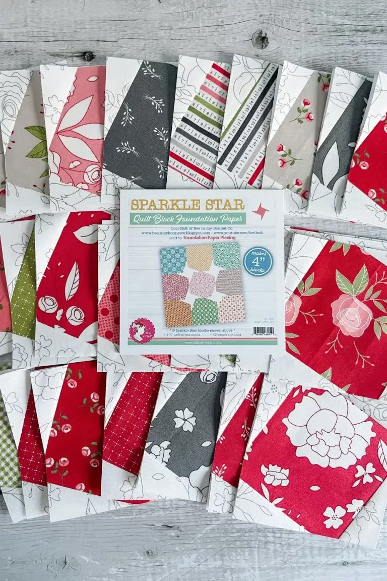 Sparkle star quilt blocks spread out with a pad of quilt block foundation paper used to make the blocks