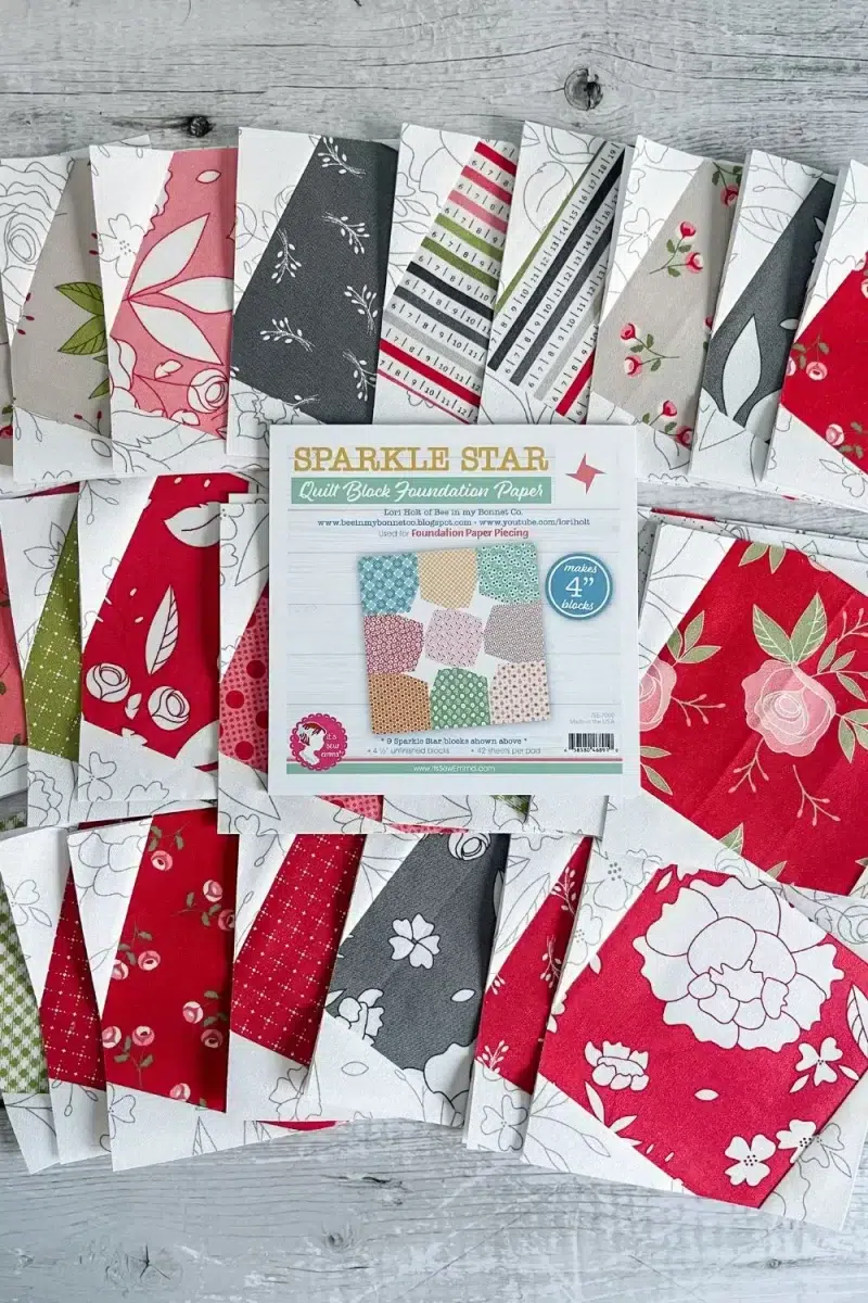 Sparkle star quilt blocks spread out with a pad of quilt block foundation paper used to make the blocks