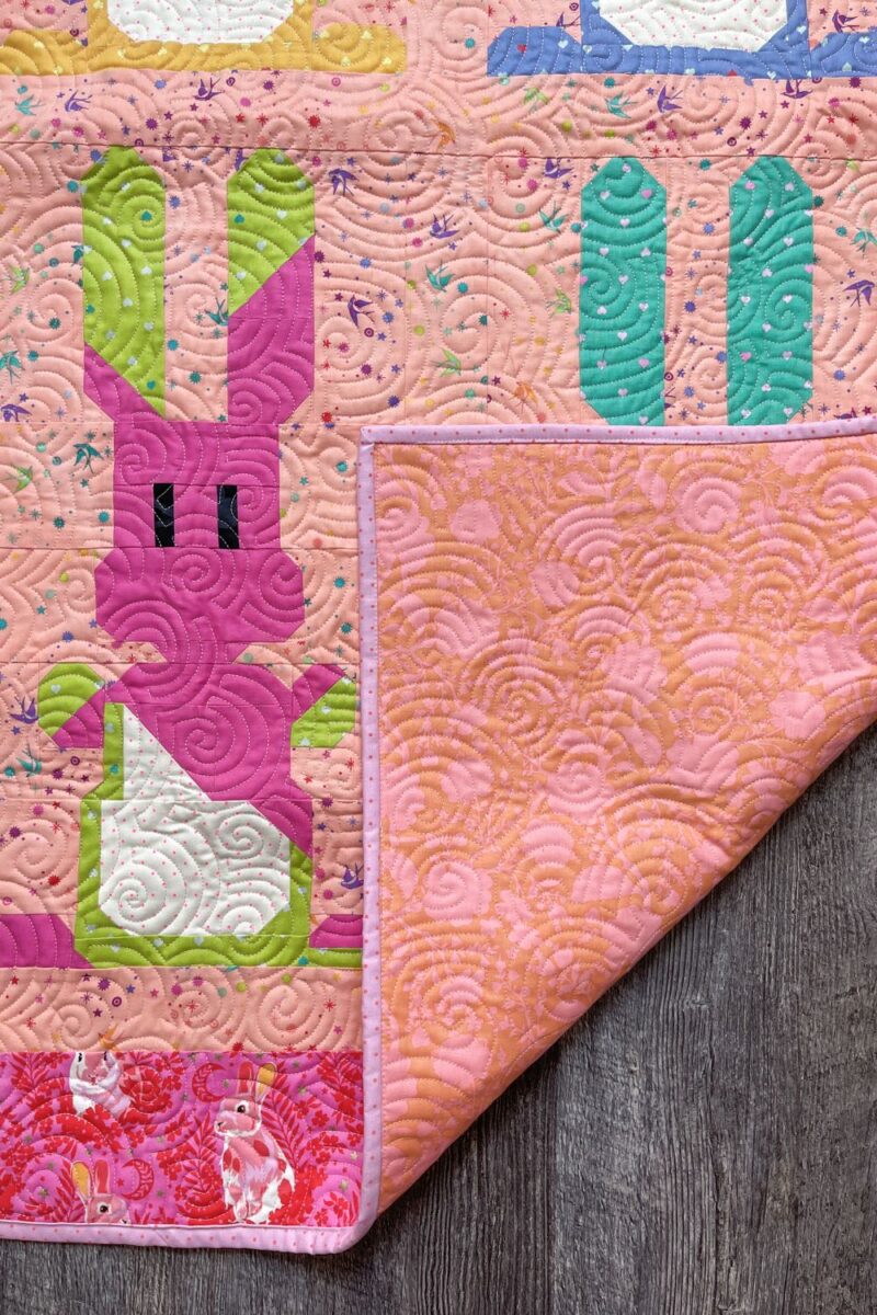 Folded corner of quilt to show the backing and binding over the top of the front of the bunny quilt.