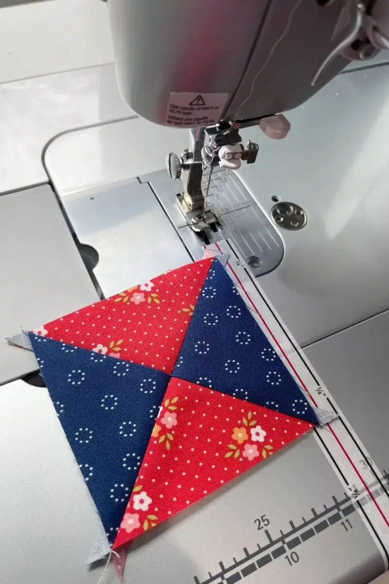 Untrimmed hourglass quilt block unit made with blue and red fabrics.