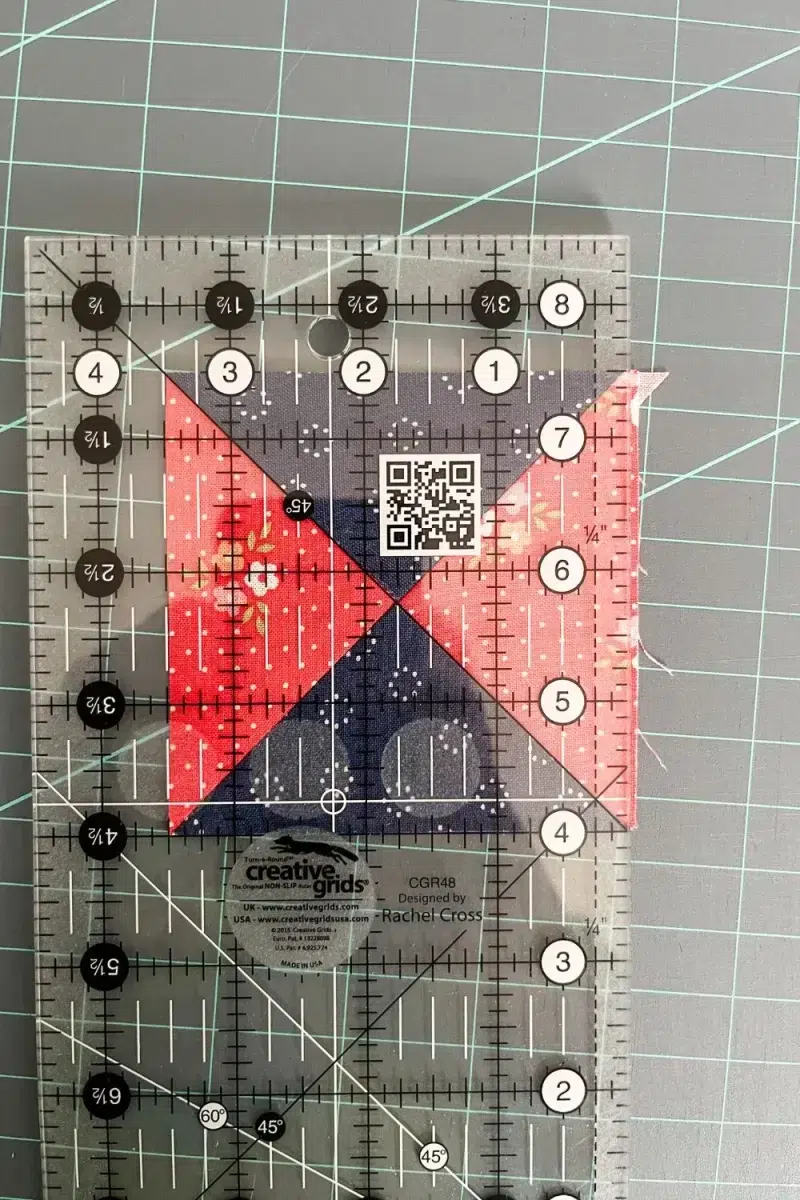 Trimming down the Hourglass quilt block using a Creative Grids ruler. The 45 degree line and the measurement marks are key to trimming the block.