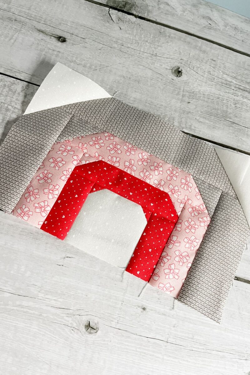 A Rainbow quilt block made with red, pink, grey, and white