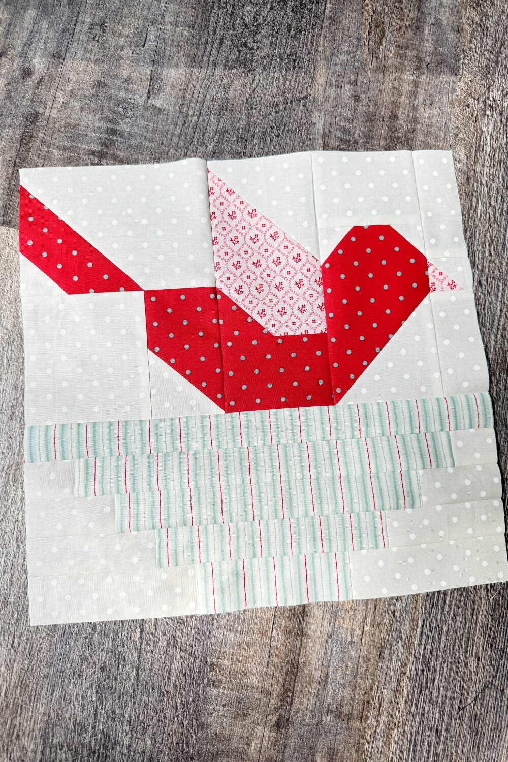Feather Your Nest quilt block of a pieced red bird in a nest.