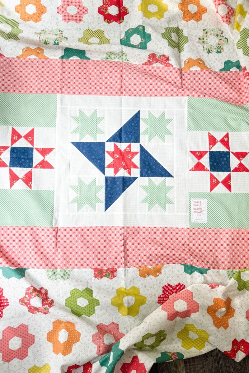 Star quilt blocks offset by fabric strips and a cheater panel of grandmother's flower garden print to finish a pieced quilt back