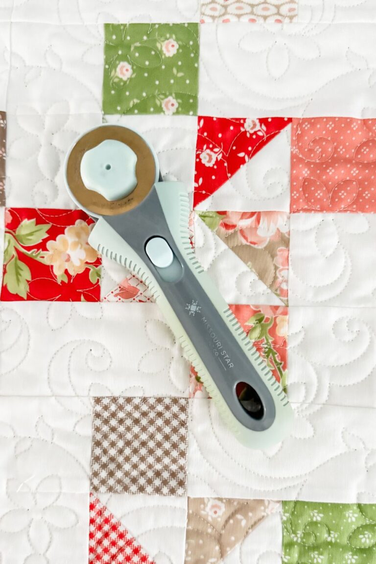 Rotary cutter on top of a finished quilt.