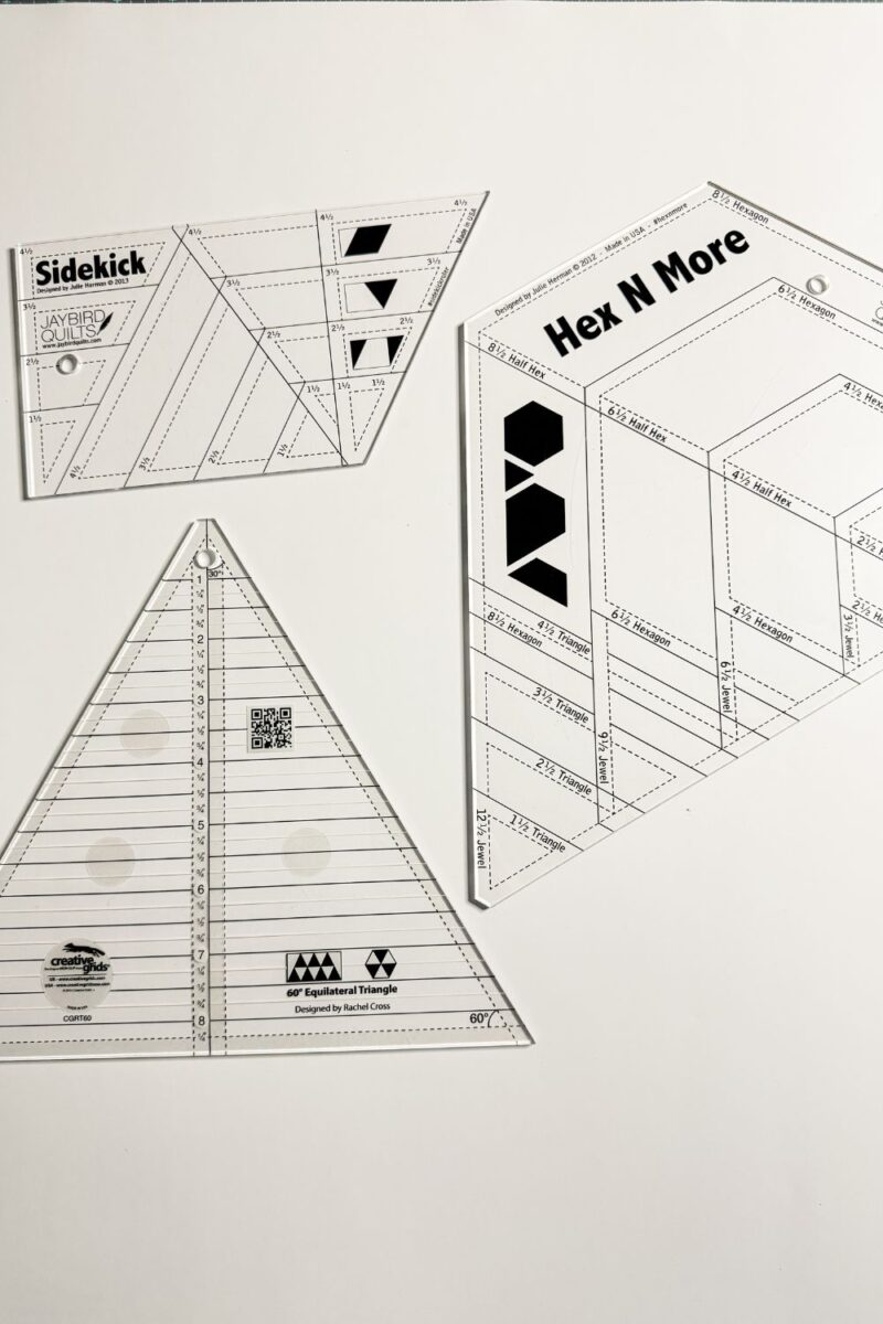 Close up of a 60 degree triangle ruler, a Sidekick ruler, and a Hex N More specialty quilting ruler