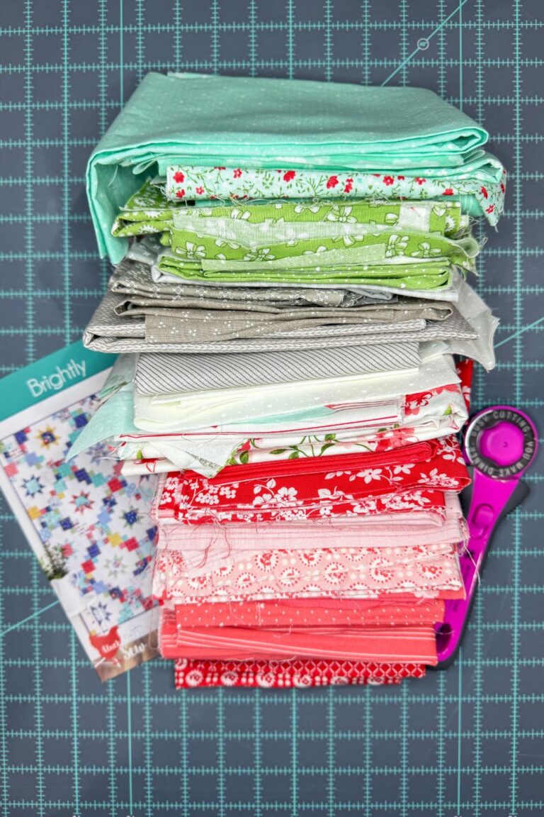 Stack of leftover quilt fabrics from another project and the Brightly quilt pattern I plan to use to make a new quilt.