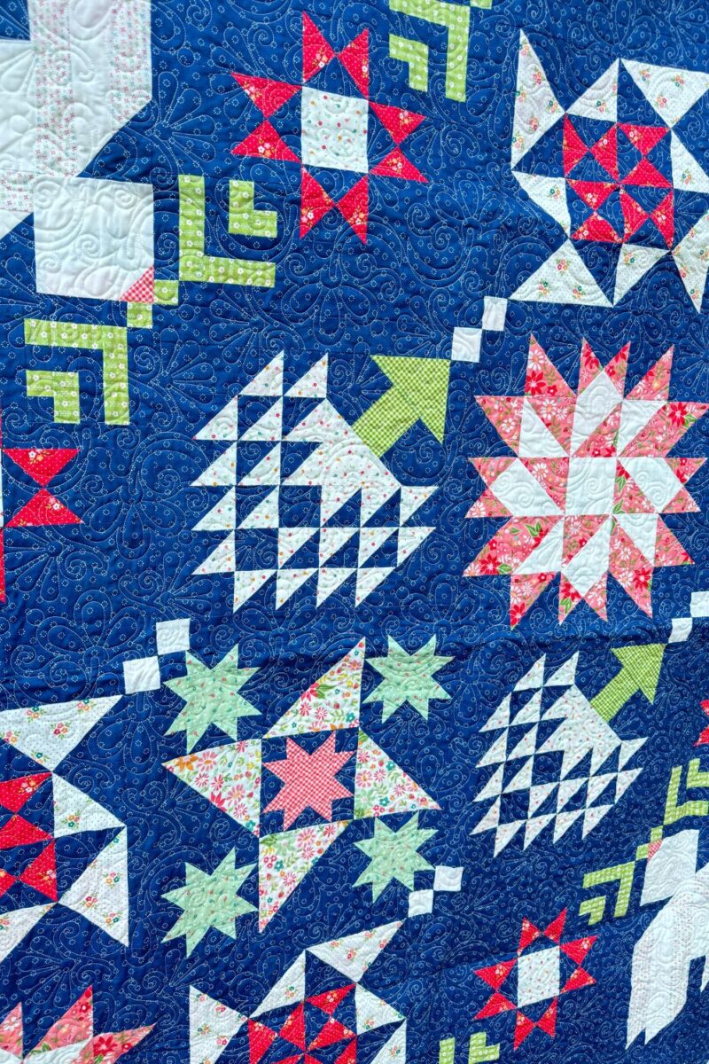 The finished Moonbeams Quilt, featuring vibrant Strawberry Lemonade fabrics, pieced blocks, and the 'Flowers Rise Again' edge-to-edge quilting pattern.
