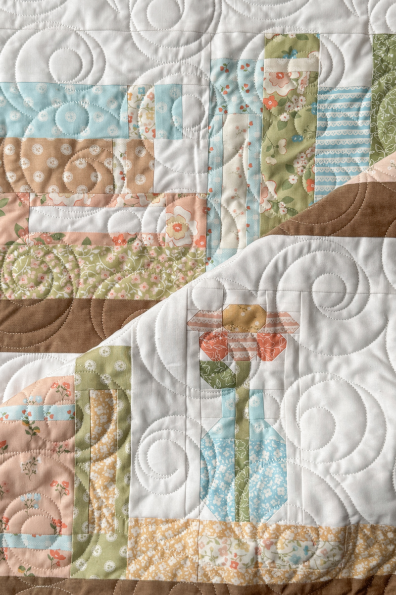 Folded quilt showing a flower-in-a-vase block and a row of book blocks