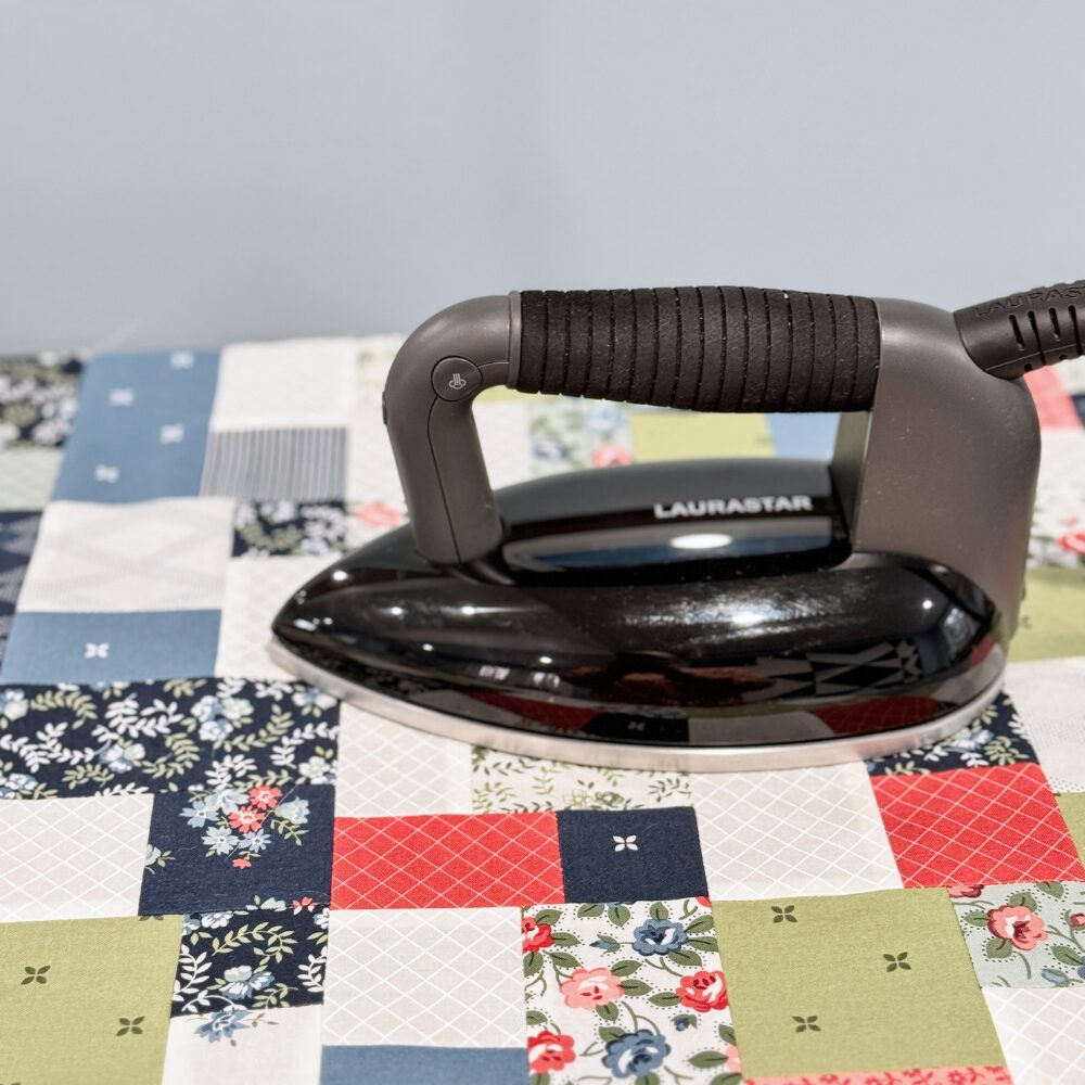 A LauraStar iron sitting on top of patchwork squares demonstrating good pressing.