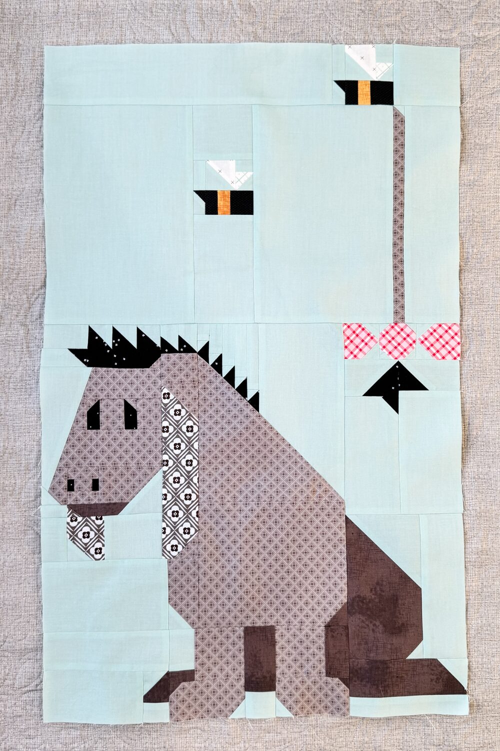 Finished Eeyore quilt block showing Eeyore’s tail in the air and bees flying.