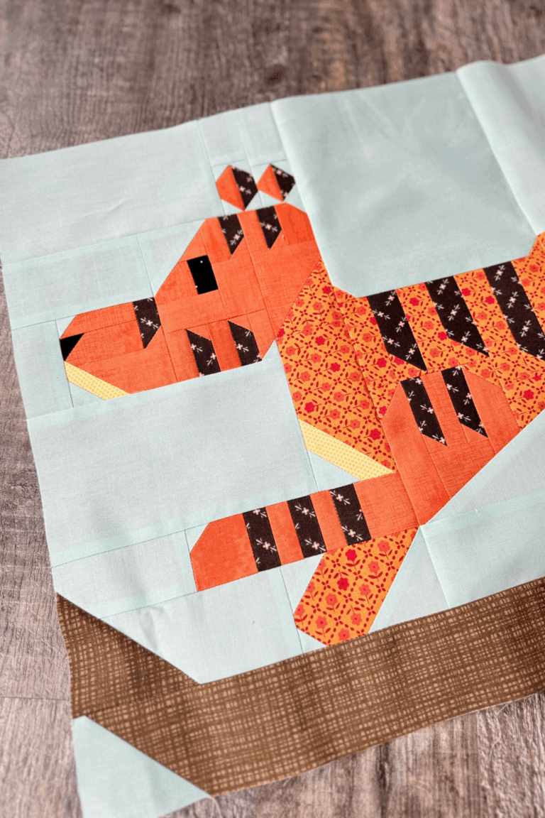 Close-up of the Tigger quilt block showing Tigger’s face and front body pieced in orange fabrics.