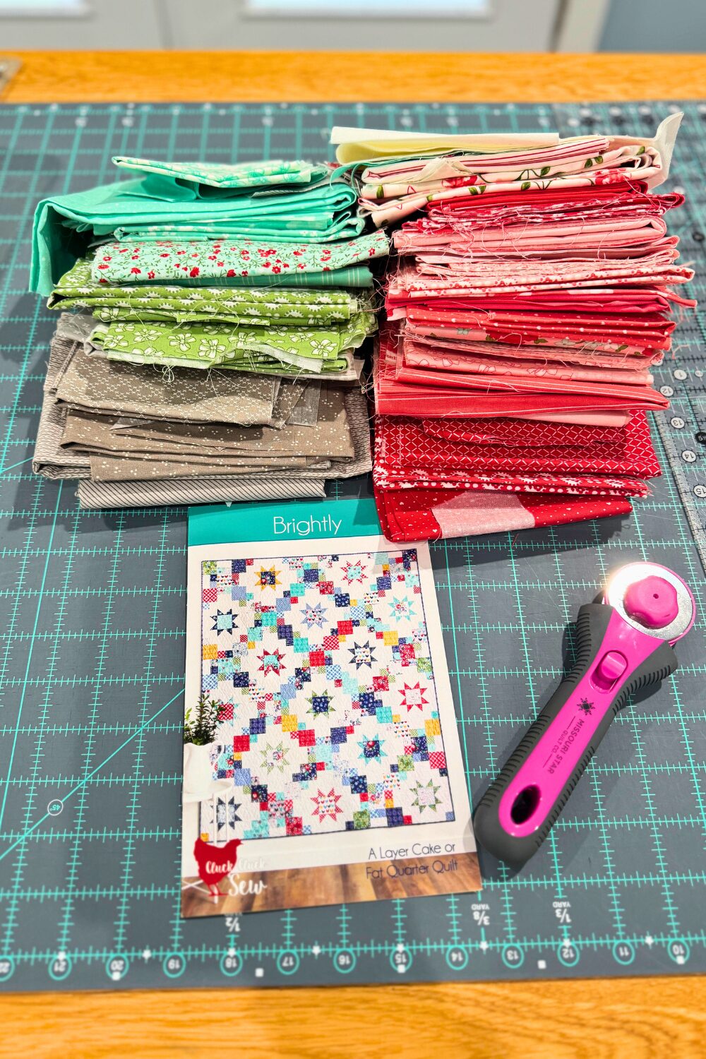 Leftover Shine Bright quilt fabrics stacked next to the Brightly quilt pattern for a future scrap project.