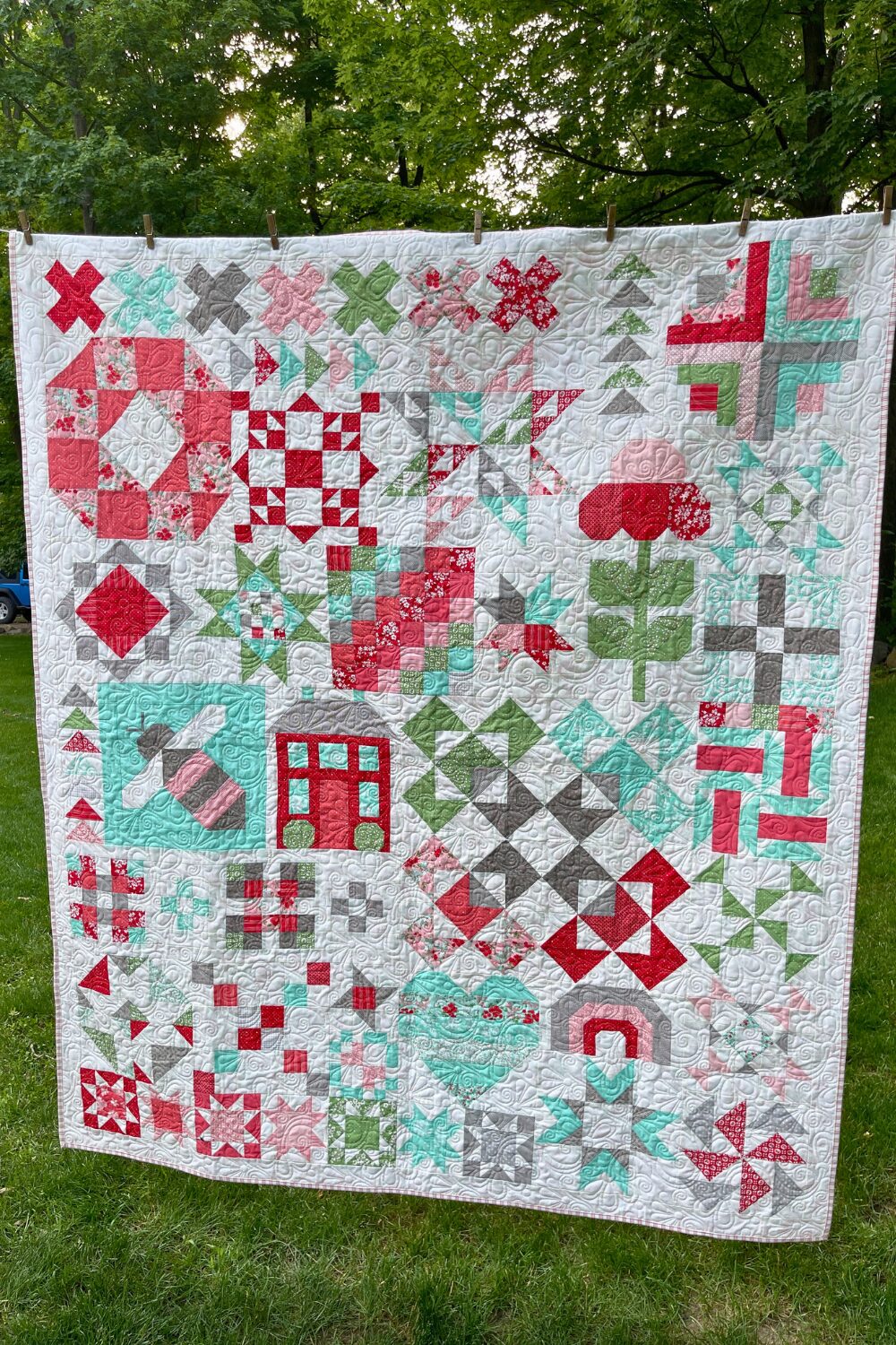 Full Shine Bright quilt hanging on a line, quilted with the Flowers Rise Again pantograph using Lighthearted fabrics.