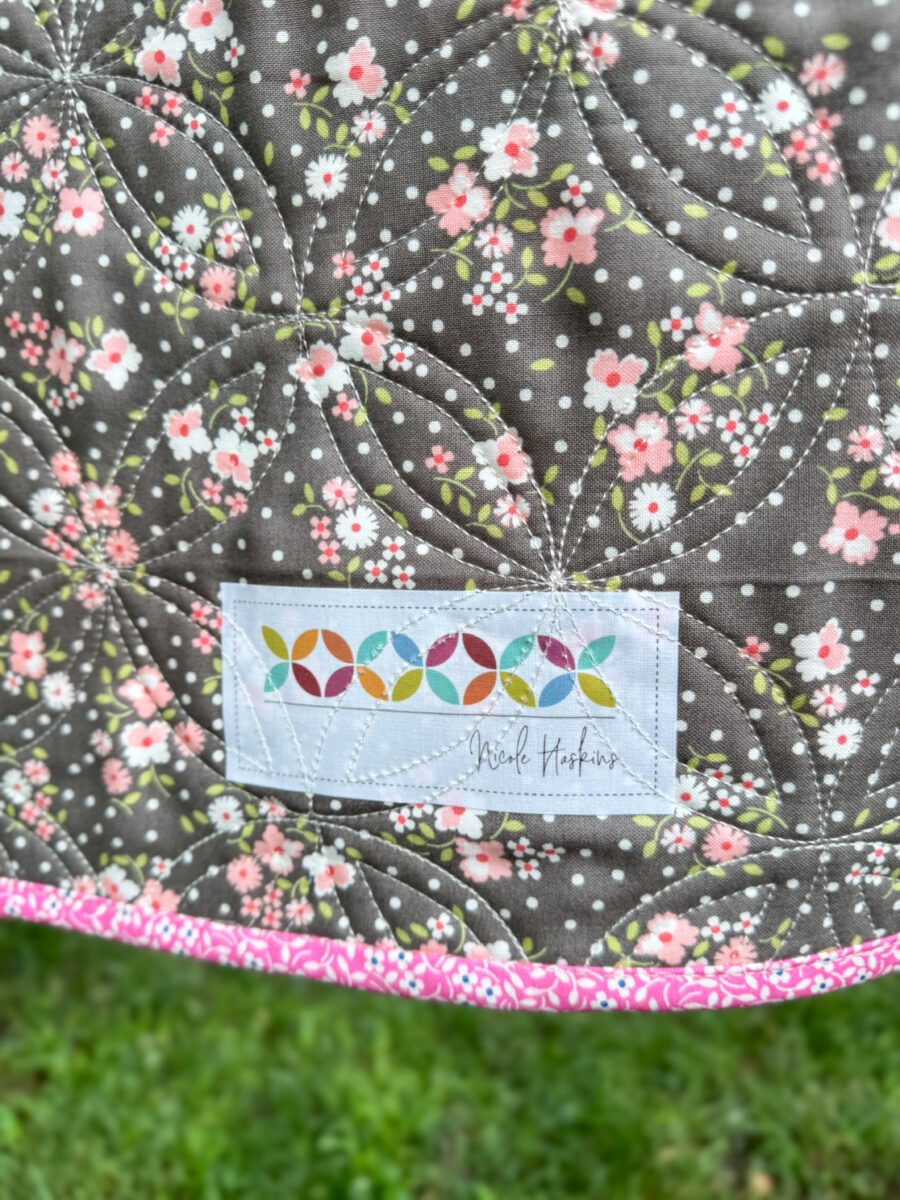 Custom quilt label on the back of the finished Strippy Spools quilt with maker info.