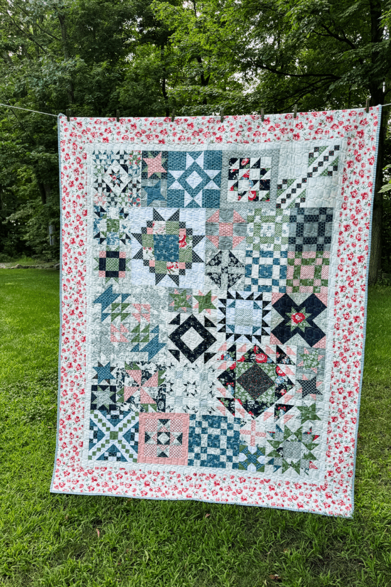 Finished Piece and Quilt Sampler quilt top hanging on a clothesline outdoors.