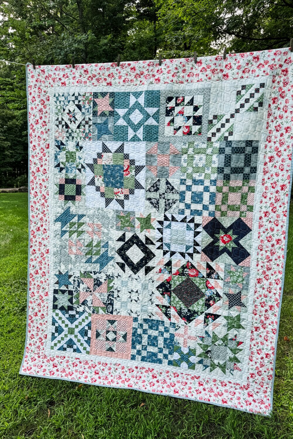 Finished Piece and Quilt Sampler quilt top hanging on a clothesline outdoors.
