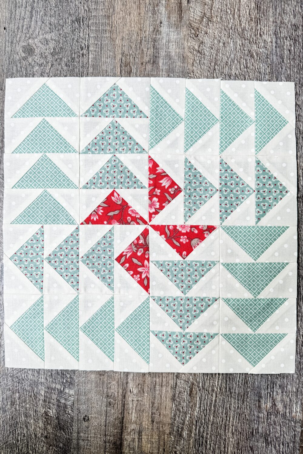 Finished 12" Family Time quilt block with red and blue flying geese forming a pinwheel.