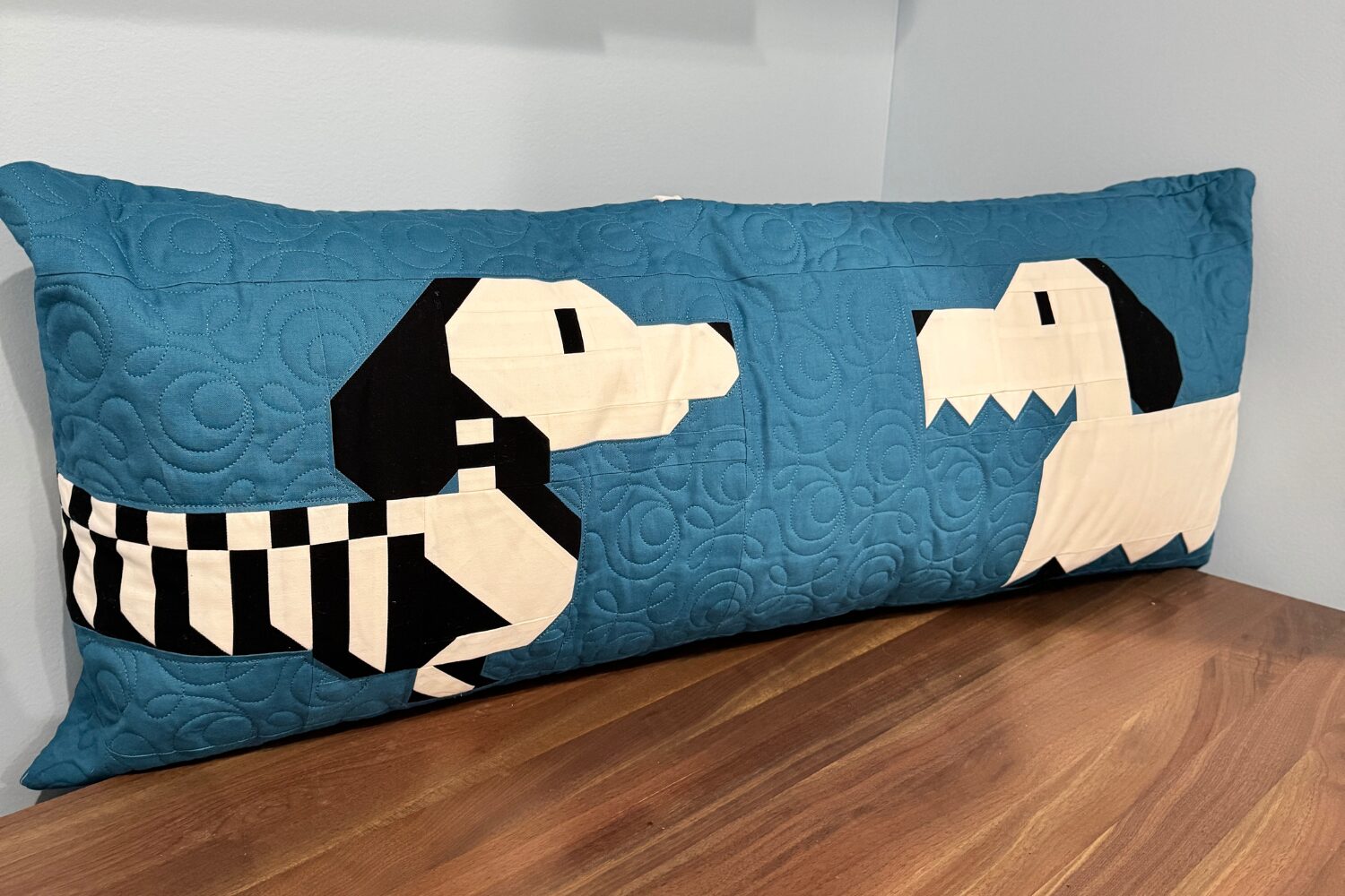 Front of Halloweenies bench pillow featuring ghost and skeleton weenie dogs facing each other on quilted blue background.