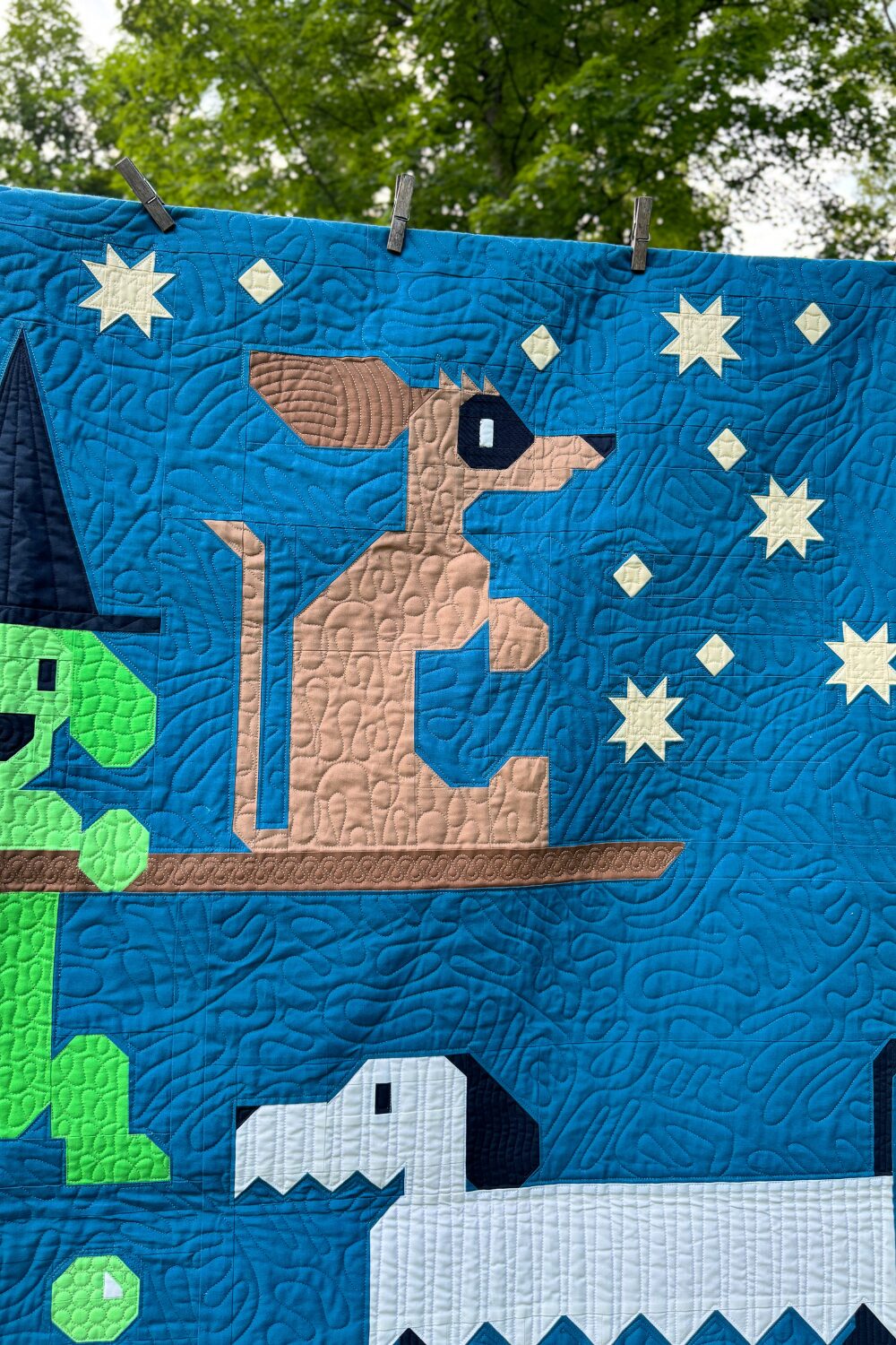 Masked weiner dog from the Halloweenies Quilt riding on a broom beside the witch dog.