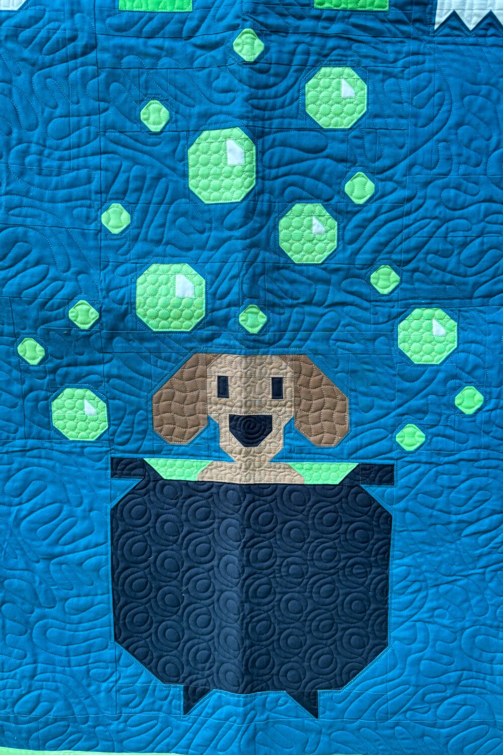 Weiner dog sitting in a bubbling cauldron block from the Halloweenies Quilt with green bubbles.